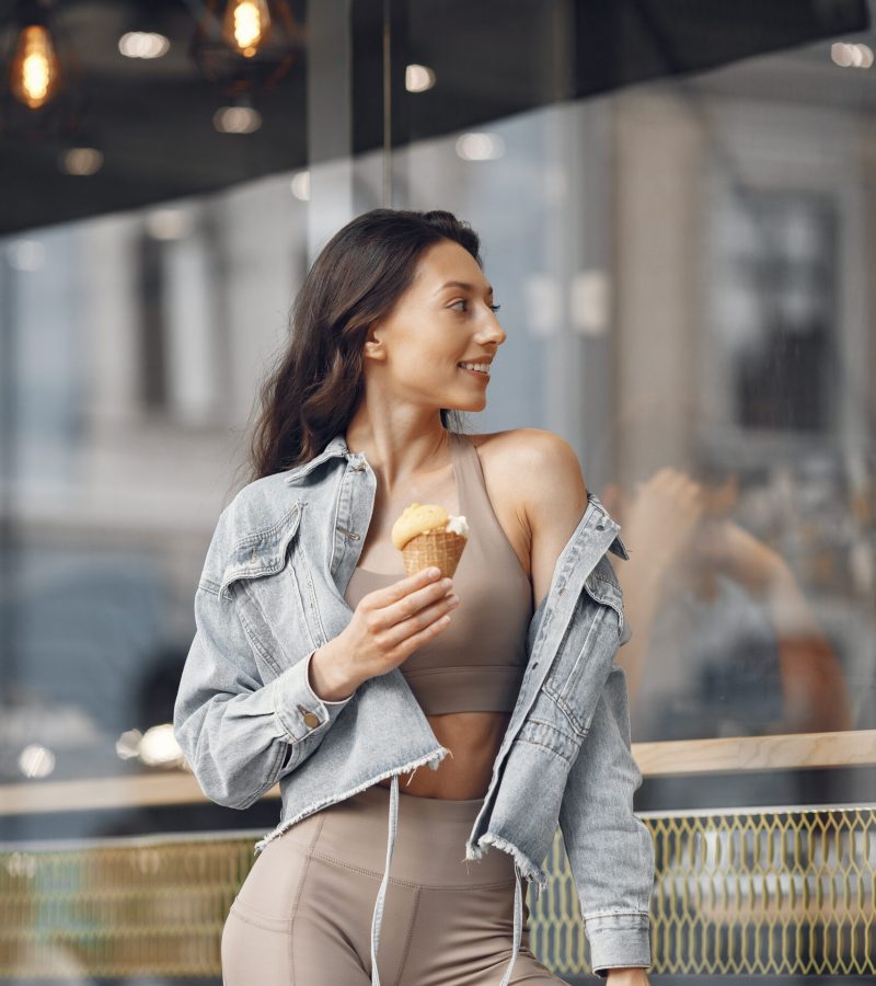 Woman in a summer city. Lady with ice cream. Brunette by the building.